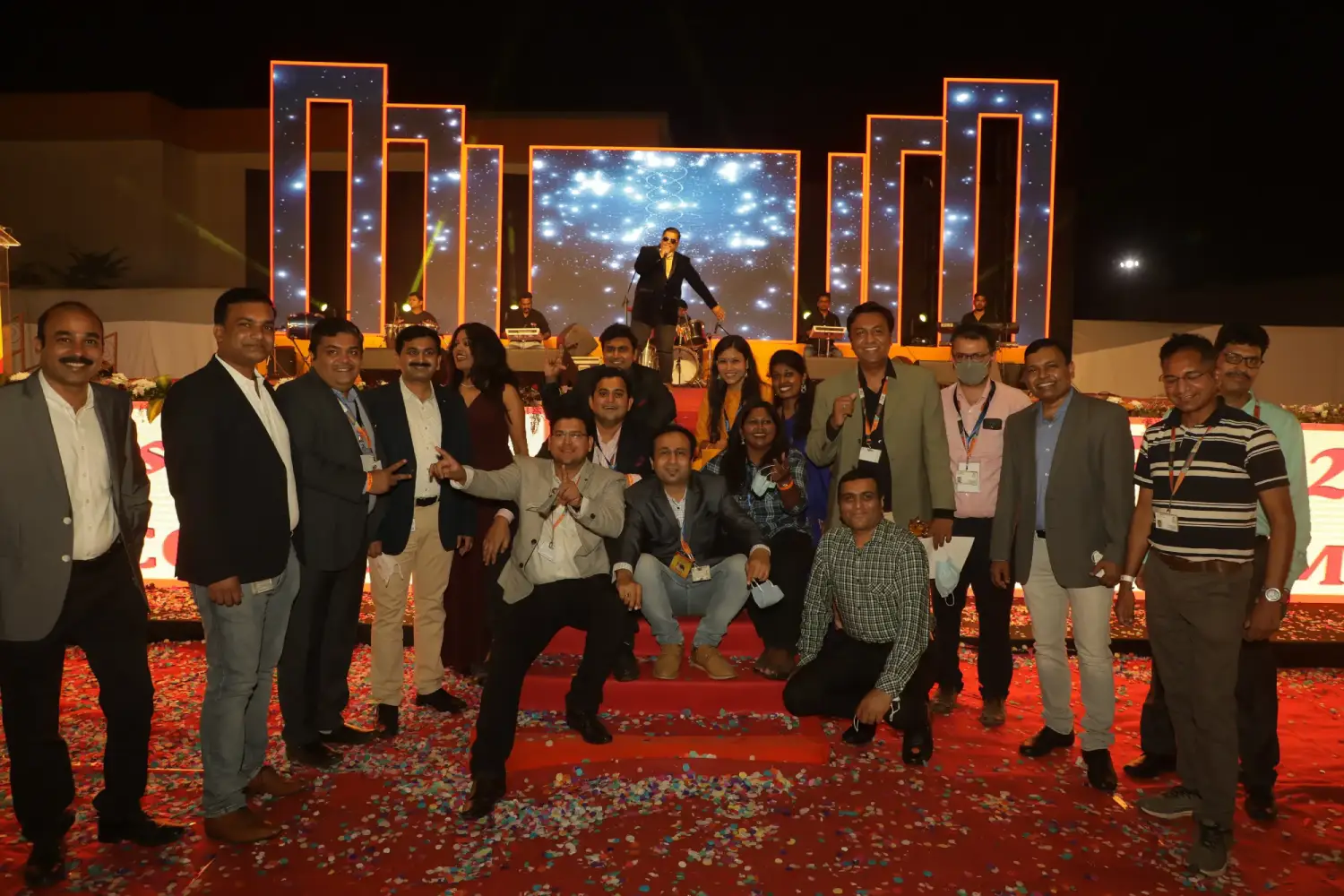 Man and woman speaking on stage at night with blue lighting